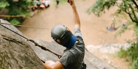 Man rock climbing on a cliff giving a thumbs up