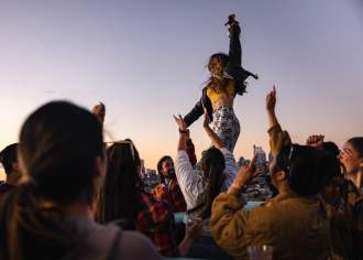 A woman dances with a crowd on a rooftop, overlooking a city skyline in Pennsylvania.