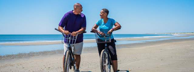 A couple enjoys a bike ride along seven miles of undeveloped beach on Little St. Simons Island, Georgia