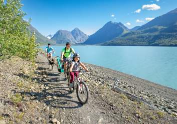 A family bikes along the shore of Eklutna Lake.