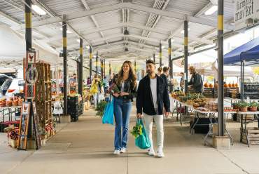 Young couple with shopping totes walking through the Ann Arbor Farmers Market