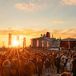 Liverpool Pier Head, busy with visitors and the sun going down across the River creating a golden light