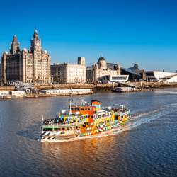 A ferry on the River Mersey with the Liverpool skyline behind it.