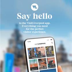 A person holding an iphone with the VisitLiverpool app against the Royal Liver building blurred in the background