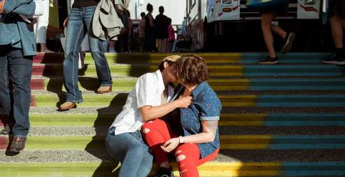 Two people kissing on stairs.