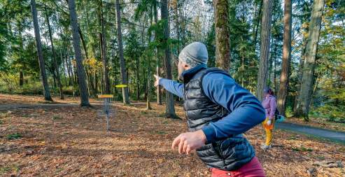 A person throwing a frisbee while playing frisbee golf.