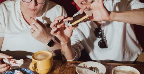 Two people eating Nanaimo bars with lattes.