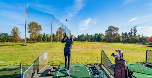 A person hitting a golf ball from a driving range.
