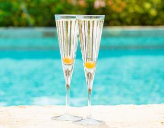 Two Champagne flutes pool side.