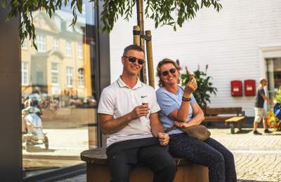 A couple enjoying an ice cream on a bench
