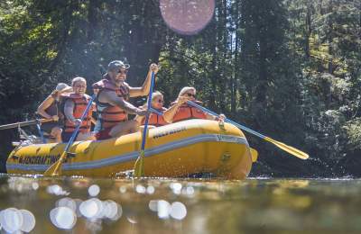 A group of people paddle on a white water raft on the McKenzie River