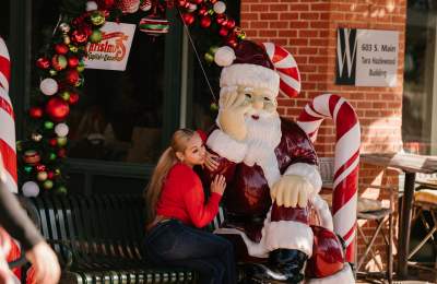 Christmas Capital of Texas woman taking picture with Santa statue