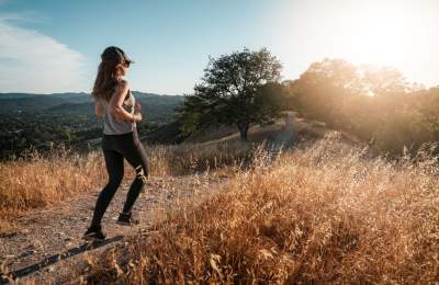 Girl running on trail in Atascadero during golden hour with a view of the sky
