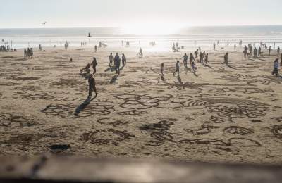 People biking, walking and creating sand art on the beach