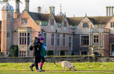 A couple walking their dog in front of Charlecote Park