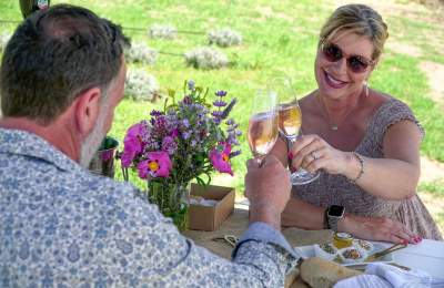 Couple at Hambly Farms celebrating with wine and food, women smiling at husband