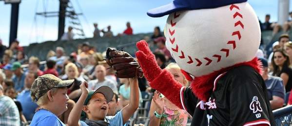 boys in baseball caps high five Screwball at a Fightin Phils game