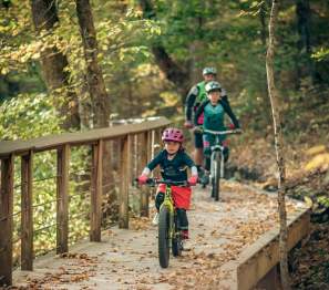 A family mountain biking through a trail in the fall at Clarksville's Rotary Park.