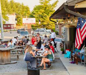 people at tables outside of a brewery