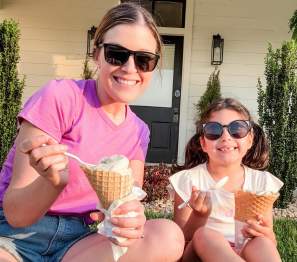 a woman and child enjoy ice cream cones in the grass