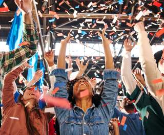 People with their arms up, cheering and confetti falls on them