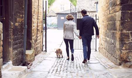 A couple walking a dog outside the Lygon Arms Hotel