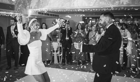 A bride and groom dancing amongst confetti, whilst friends and family watch, at Ellenborough Park