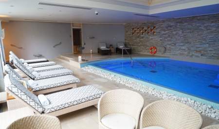 Padded sunbeds sit alongside an indoor pool at Cotswold House Hotel & Spa in the Cotswolds