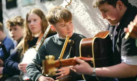 Piper and guitar player sitting side by side performing