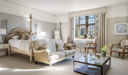 A four poster bed catches the morning light through a leaded window
