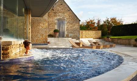 A lady relaxing in an outdoor spa pool at the Aquarias Spa at Whatley Manor in the Cotswolds