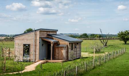 A wooden lodge surrounded by open grassland at Cotswold Farm park in the Cotswolds