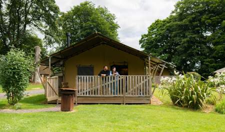 Couple looking out from the veranda of a safari lodge at Notgrove in the Cotswolds