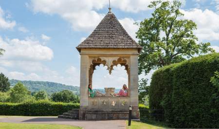 Two ladies pose for a photo in an ornate folly in the stunning grounds of Ellenborough Park, in the Cotswolds