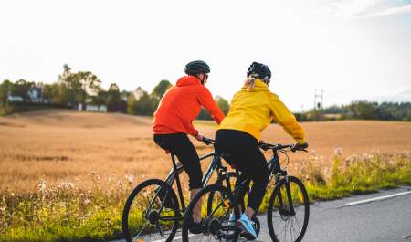Two cycling along a cornfield