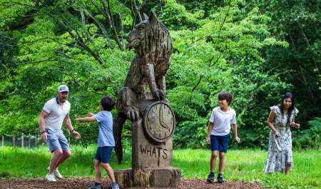 Family playing around wooden statue at Westonbirt Arboretum