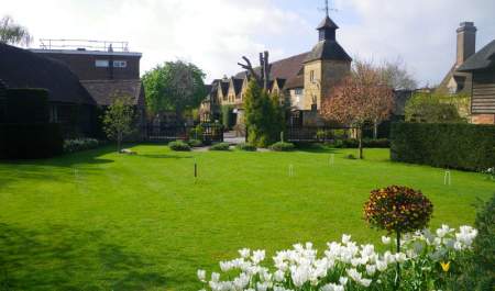 An open lawn set for croquet with a border of white tulips at The Lygon Arms in the Cotswolds