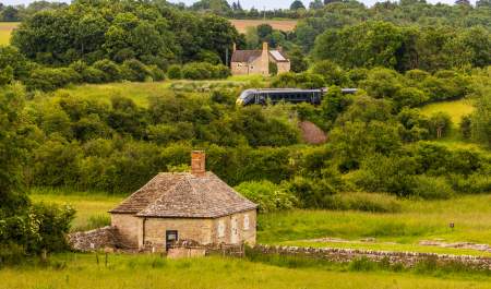 A view of North Leigh Roman Villa with a GWR train passing in the distance behind