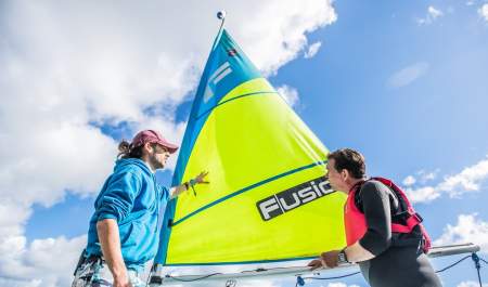 two men in front of a sailing boat