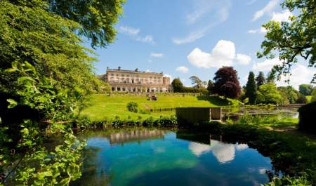 The stunning, Grade II listed Cowley Manor mansion lies in the distance with lush green lawns in front leading down to a large pond