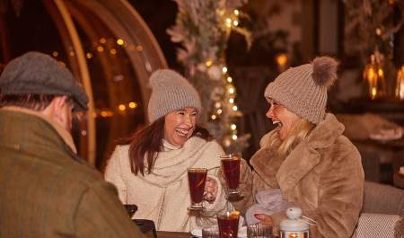 Two ladies in bobble hats enjoying mulled wine at a Christmas market at Wild Thyme and Honey