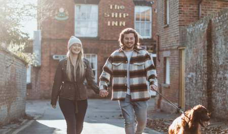 Couple with dog walking down a lane near a pub in Sewerby, East Yorkshire