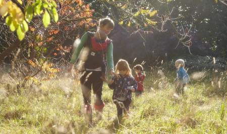 Mother and children walking through long grass and autumn trees