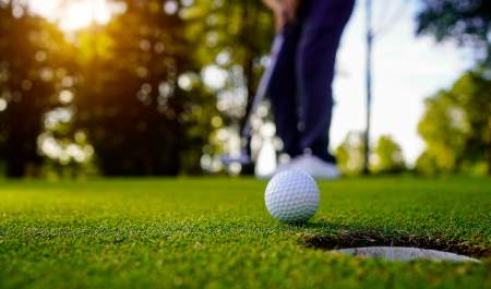 Golfball foran et hull på golfbanen