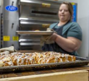 Baker at Seraphim Bread in Salina Kansas pulling fresh pastries out of the oven