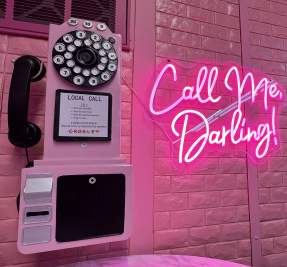 pink wall telephone beside a pink neon sign