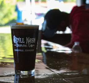 guy at a bar with a glass of dark beer
