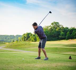 man teeing off at a golf course