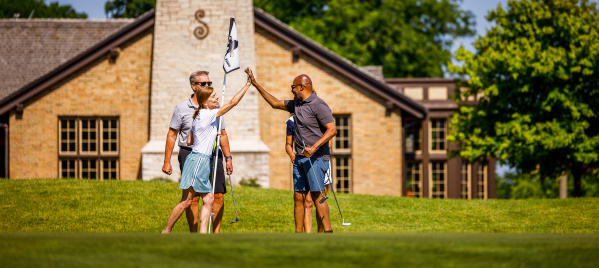 friends high-five over golf hole