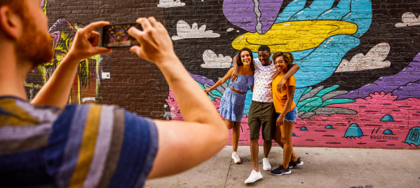 friends taking a picture in front of a colorful mural